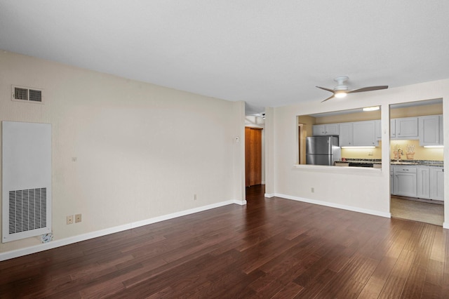 unfurnished living room with visible vents, baseboards, dark wood-type flooring, and ceiling fan