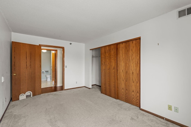 unfurnished bedroom with a closet, visible vents, a textured ceiling, and carpet floors