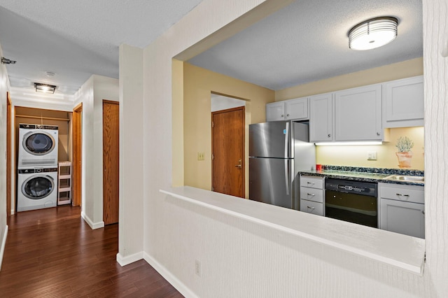 kitchen featuring visible vents, dark wood-type flooring, dishwasher, freestanding refrigerator, and stacked washer / drying machine