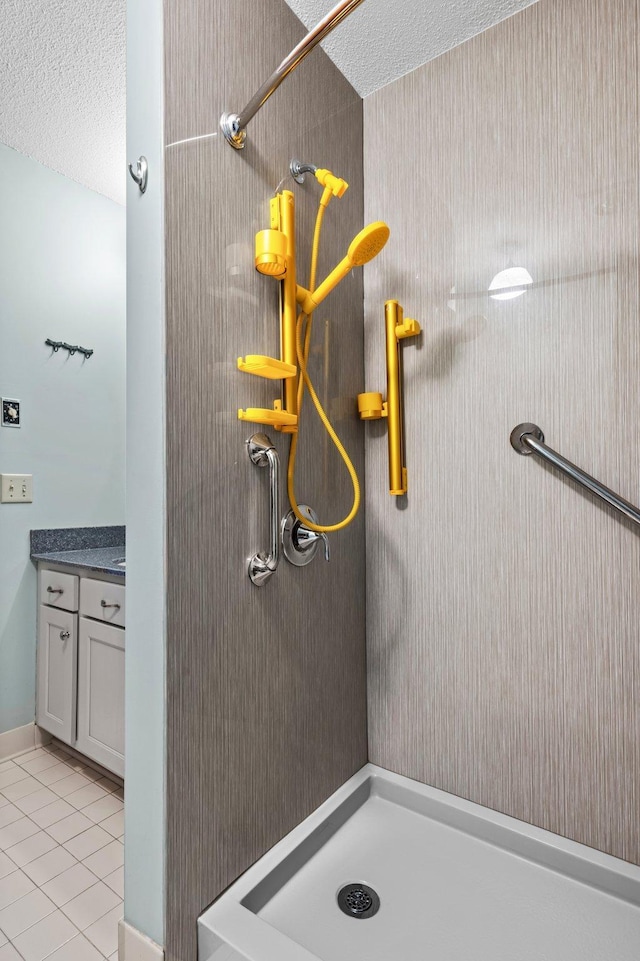 bathroom featuring tile patterned flooring, a shower stall, a textured ceiling, and vanity