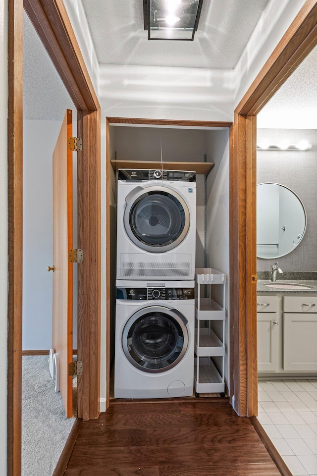 washroom featuring a sink, wood finished floors, and stacked washer and dryer