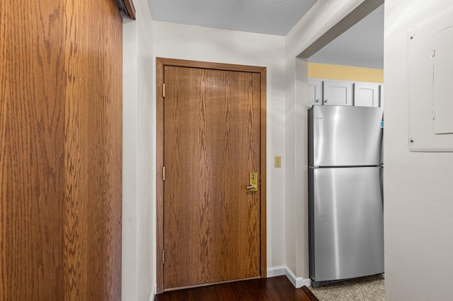 interior space featuring baseboards, a textured ceiling, and freestanding refrigerator