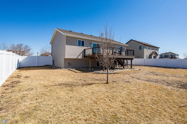 back of property with a wooden deck, a fenced backyard, and a yard
