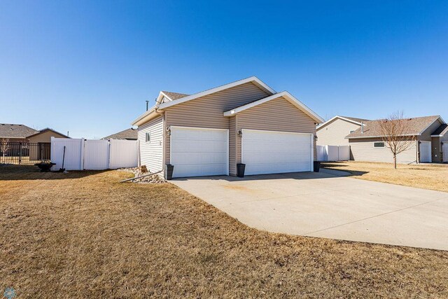 view of front of house featuring a front lawn, fence, driveway, and an attached garage