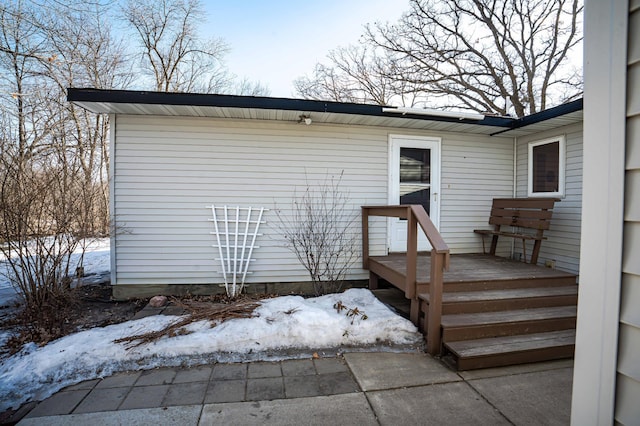 snow covered property entrance with a wooden deck