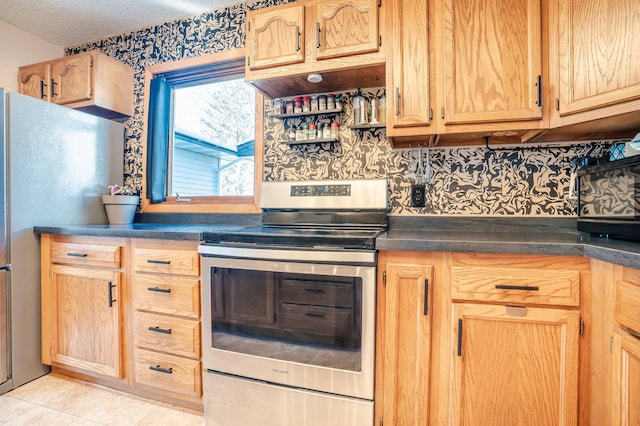 kitchen with dark countertops, light brown cabinetry, light tile patterned floors, stainless steel appliances, and a textured ceiling