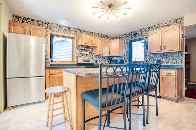 kitchen with stainless steel appliances, plenty of natural light, light brown cabinets, and a kitchen breakfast bar