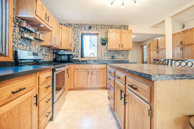 kitchen featuring light tile patterned flooring, a sink, electric stove, black microwave, and dark countertops