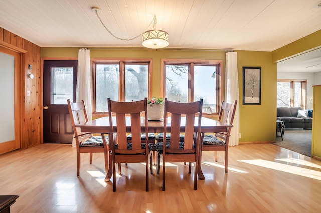 dining space featuring light wood-style flooring, wood ceiling, and baseboards