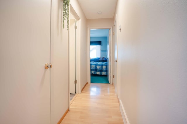 corridor with baseboards and light wood-style floors