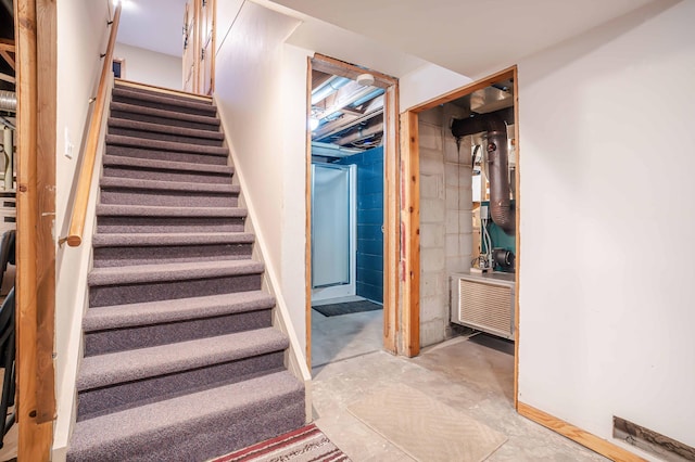 stairway with concrete block wall and unfinished concrete floors