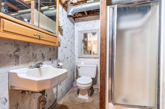 full bathroom featuring toilet, a shower with shower door, and a sink