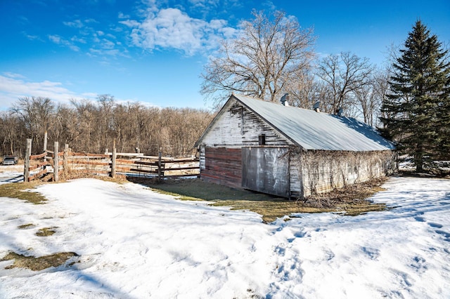 snow covered structure with an outdoor structure and fence