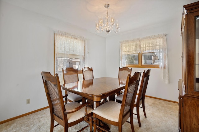 dining room with an inviting chandelier, light colored carpet, and baseboards