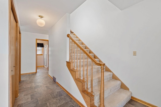 stairs featuring stone finish floor, visible vents, and baseboards