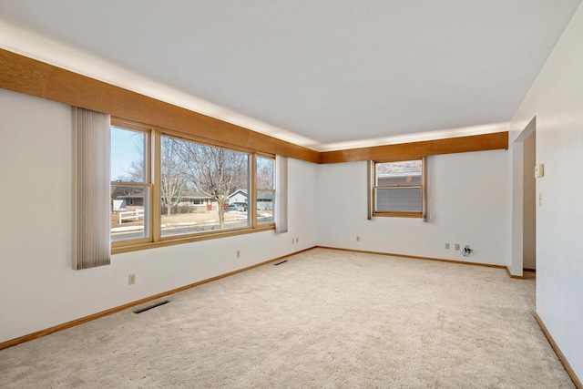 spare room with visible vents, baseboards, and light colored carpet