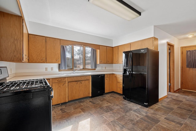 kitchen featuring a sink, stone finish flooring, black appliances, and light countertops