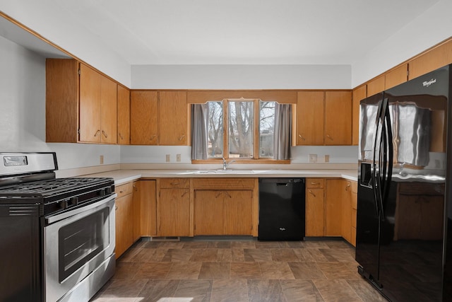 kitchen featuring a sink, stone finish floor, black appliances, and light countertops