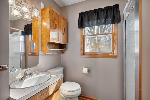 bathroom featuring toilet, vanity, and a shower with shower door