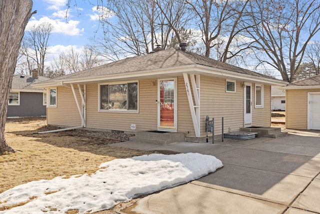 view of front of property with a garage, roof with shingles, and driveway