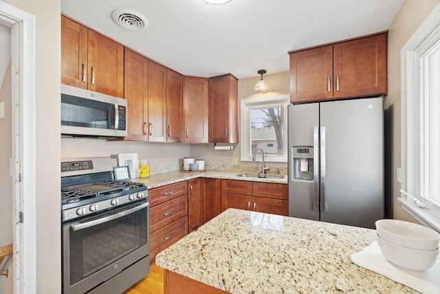 kitchen featuring a sink, visible vents, appliances with stainless steel finishes, and brown cabinetry