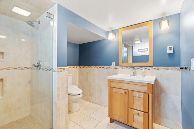 bathroom featuring a tile shower, tile patterned floors, tile walls, and vanity