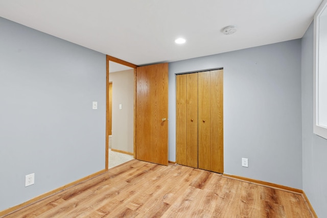 unfurnished bedroom featuring a closet, baseboards, and wood finished floors