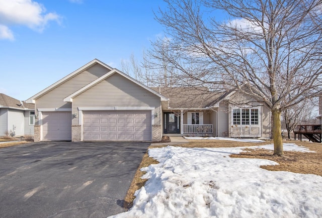 single story home featuring aphalt driveway, covered porch, an attached garage, and brick siding