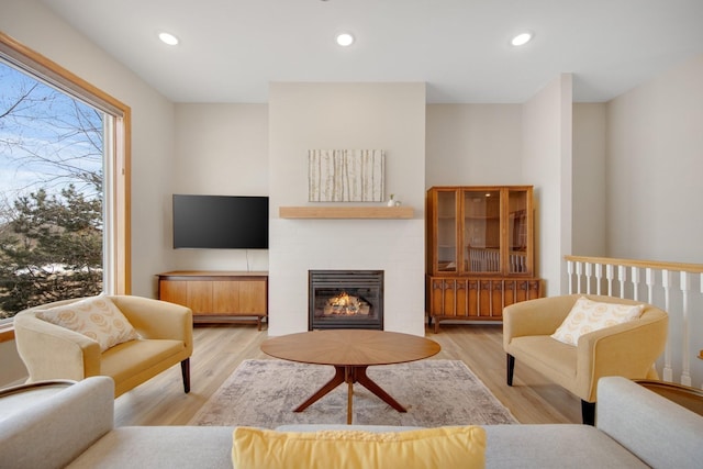 living room with recessed lighting, a brick fireplace, and wood finished floors