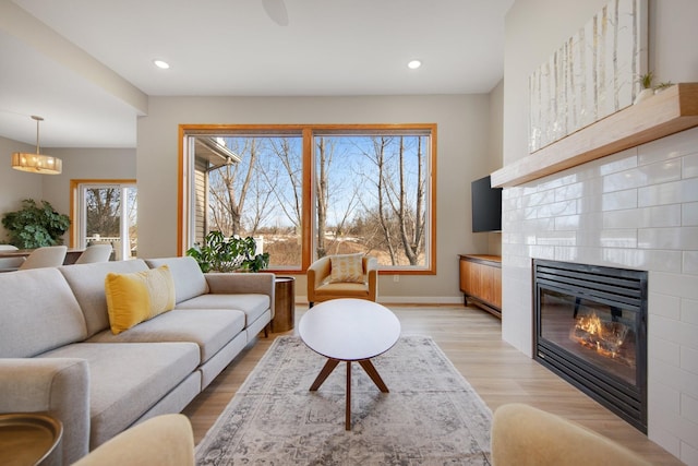 living room with recessed lighting, light wood-type flooring, baseboards, and a tile fireplace