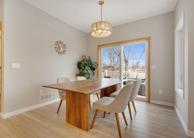 dining area featuring light wood finished floors, visible vents, a notable chandelier, and baseboards