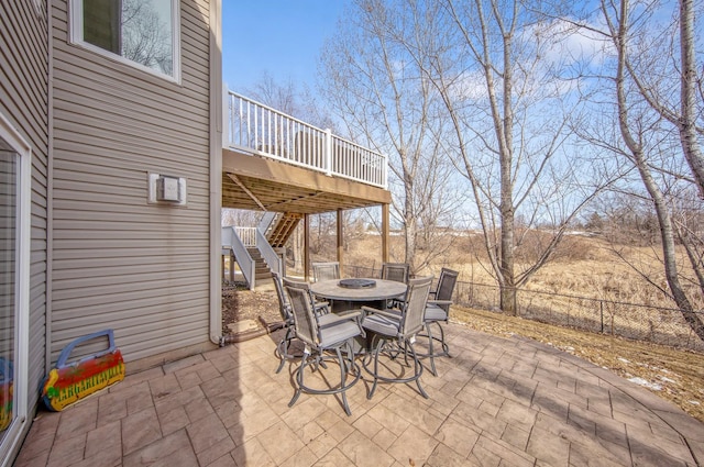 view of patio / terrace featuring outdoor dining space, stairway, fence, and a wooden deck