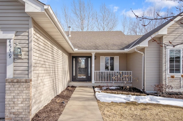 entrance to property featuring roof with shingles and a porch