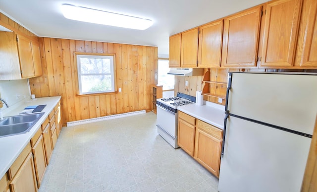 kitchen with a sink, white appliances, wooden walls, light countertops, and a baseboard radiator