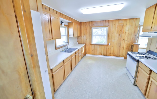 kitchen with a sink, under cabinet range hood, white gas stove, and light countertops