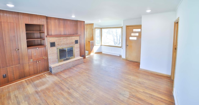 unfurnished living room featuring a brick fireplace, recessed lighting, baseboards, and light wood finished floors