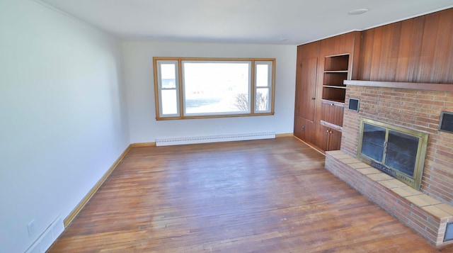 unfurnished living room featuring a baseboard heating unit, built in shelves, a fireplace, and wood-type flooring