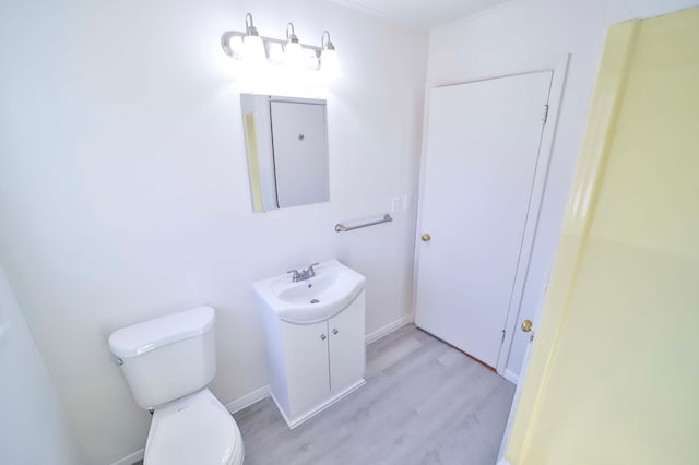 bathroom featuring vanity, toilet, wood finished floors, and baseboards