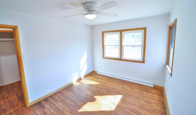 unfurnished bedroom featuring hardwood / wood-style floors, a closet, a baseboard radiator, baseboards, and ceiling fan