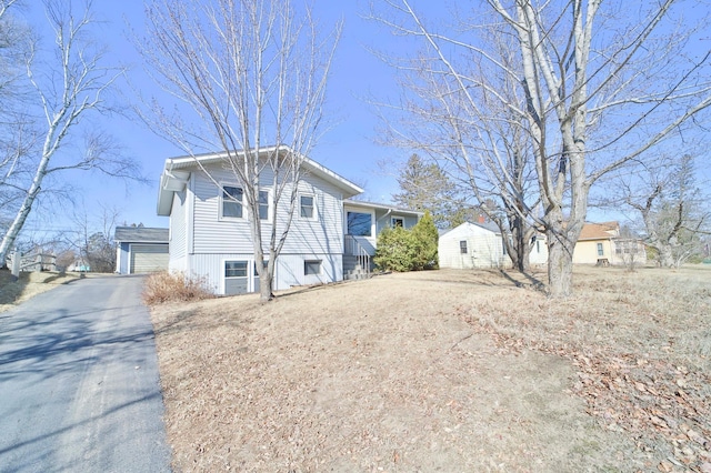 view of front facade with aphalt driveway, a garage, and an outdoor structure