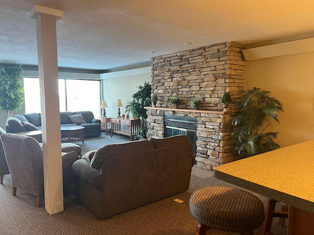 living area with a stone fireplace, carpet floors, and a textured ceiling