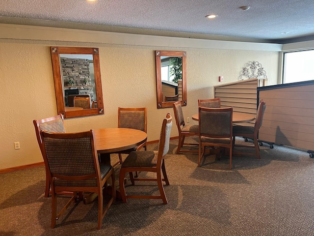 dining room with baseboards, a textured ceiling, carpet, and a textured wall