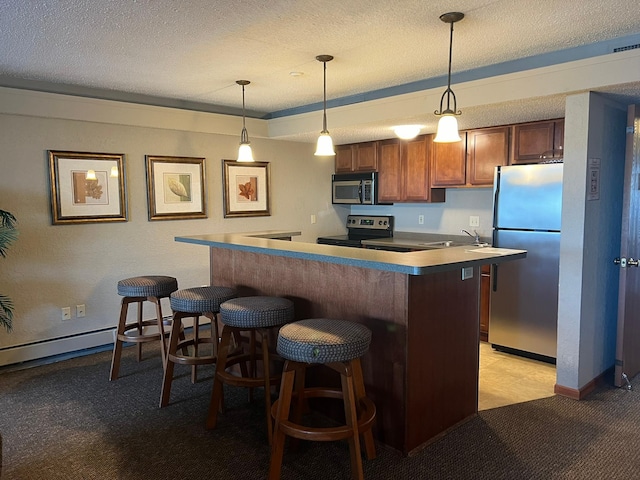 kitchen featuring stainless steel appliances, a kitchen bar, a textured ceiling, and hanging light fixtures