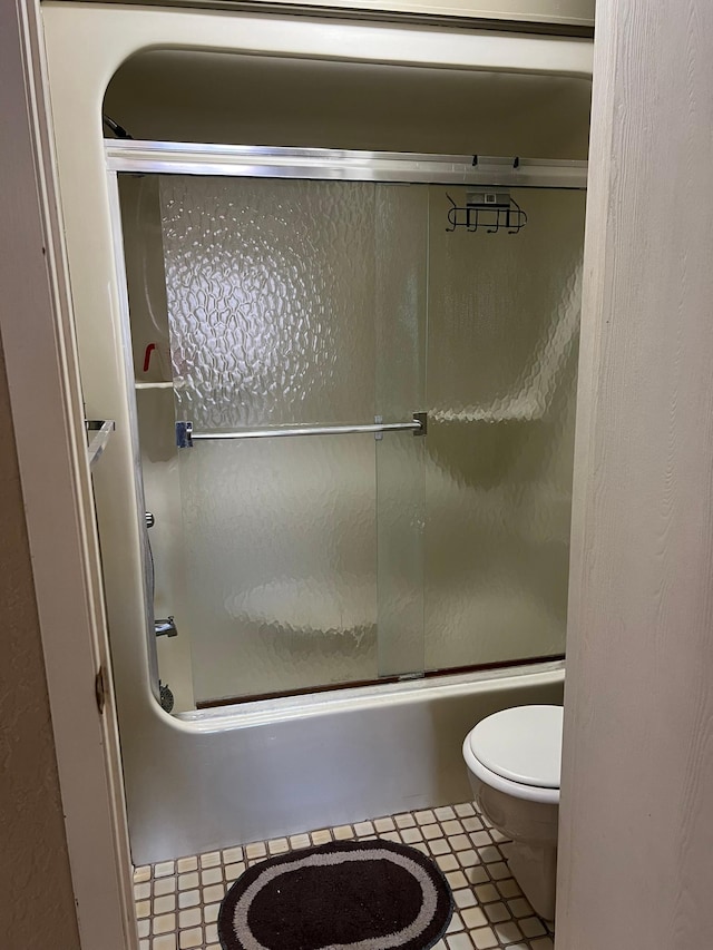 full bathroom with tile patterned floors, toilet, and shower / bath combination with glass door