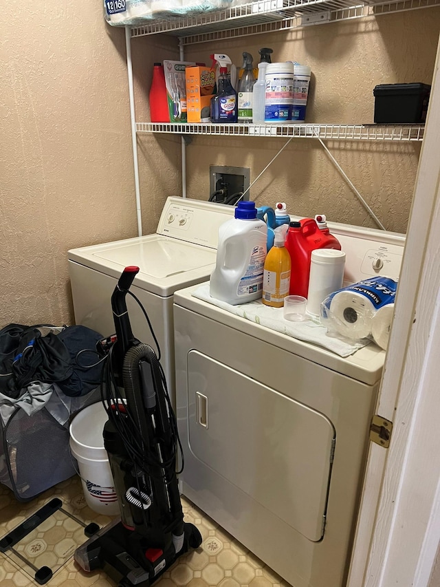 laundry room with laundry area, tile patterned floors, washing machine and dryer, and a textured wall