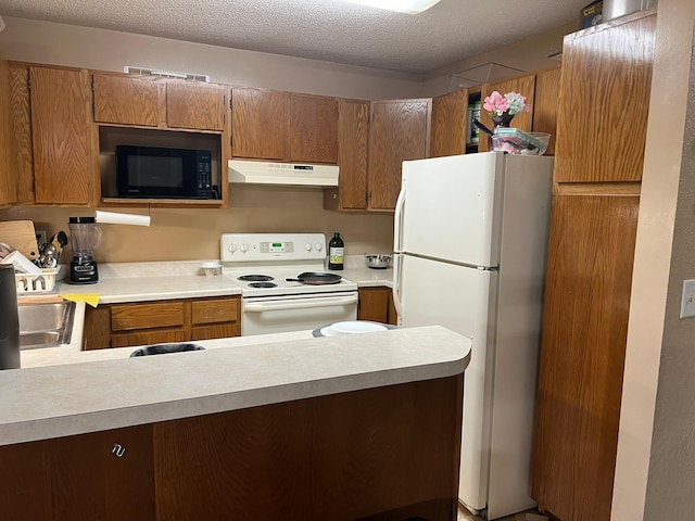 kitchen with white appliances, light countertops, under cabinet range hood, and a textured ceiling