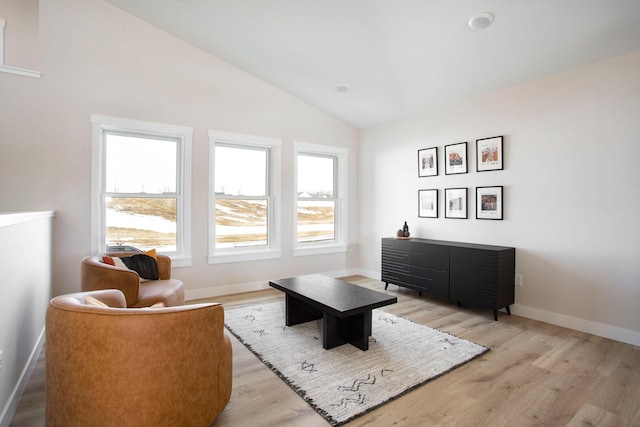 sitting room with baseboards, lofted ceiling, and light wood-style flooring