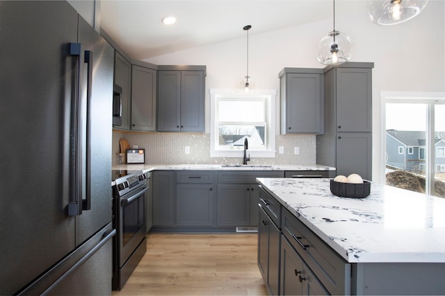 kitchen featuring vaulted ceiling, gray cabinets, appliances with stainless steel finishes, and a sink