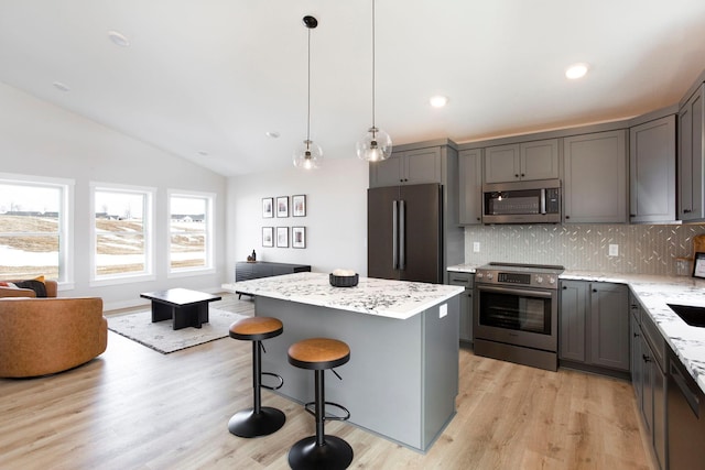 kitchen featuring backsplash, a center island, vaulted ceiling, gray cabinets, and stainless steel appliances