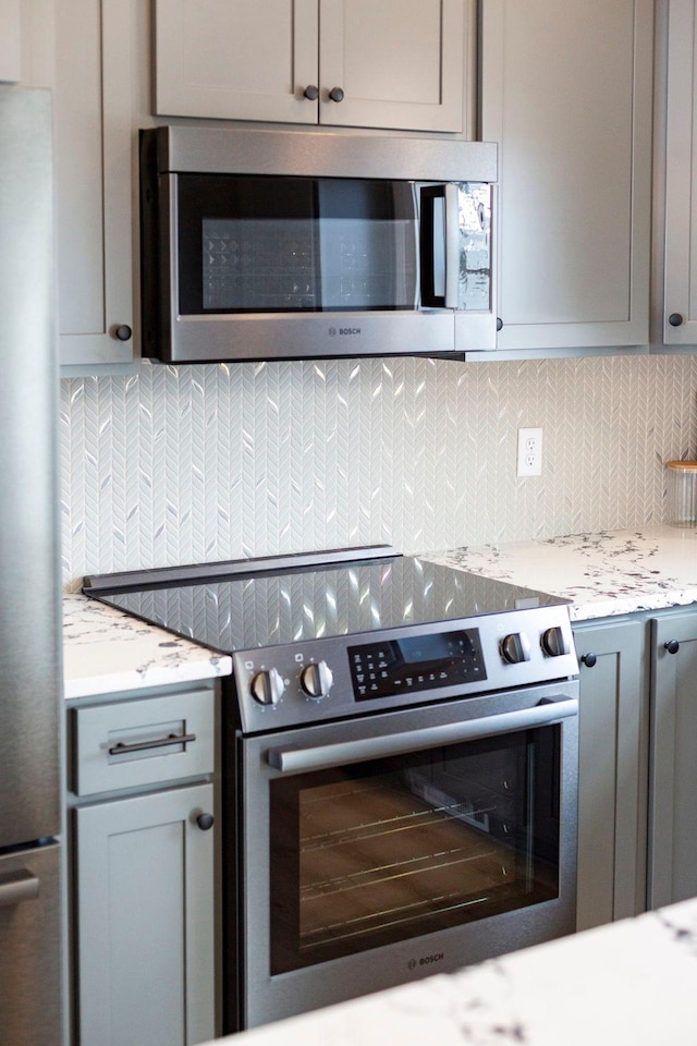 kitchen with backsplash, appliances with stainless steel finishes, and gray cabinetry